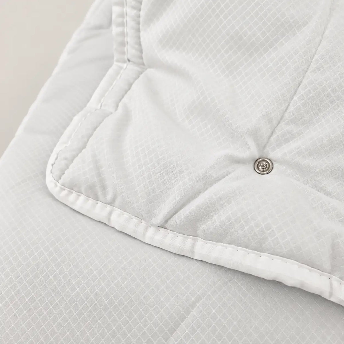 Detail of the snap-button system on the Eco duvet for attaching it to the 100 g model to create a 4-season duvet. - Oma Home
