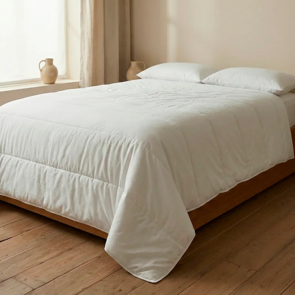 Double bed dressed with Oma Home’s 100 g eco-friendly summer duvet, showcasing its lightness and natural drape in white.