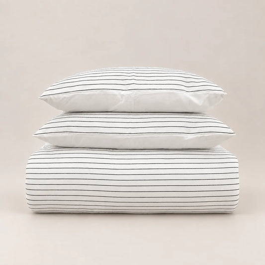 Couette d’hiver au motif jacquard à fines rayures, soigneusement pliée avec deux taies d’oreiller assorties.