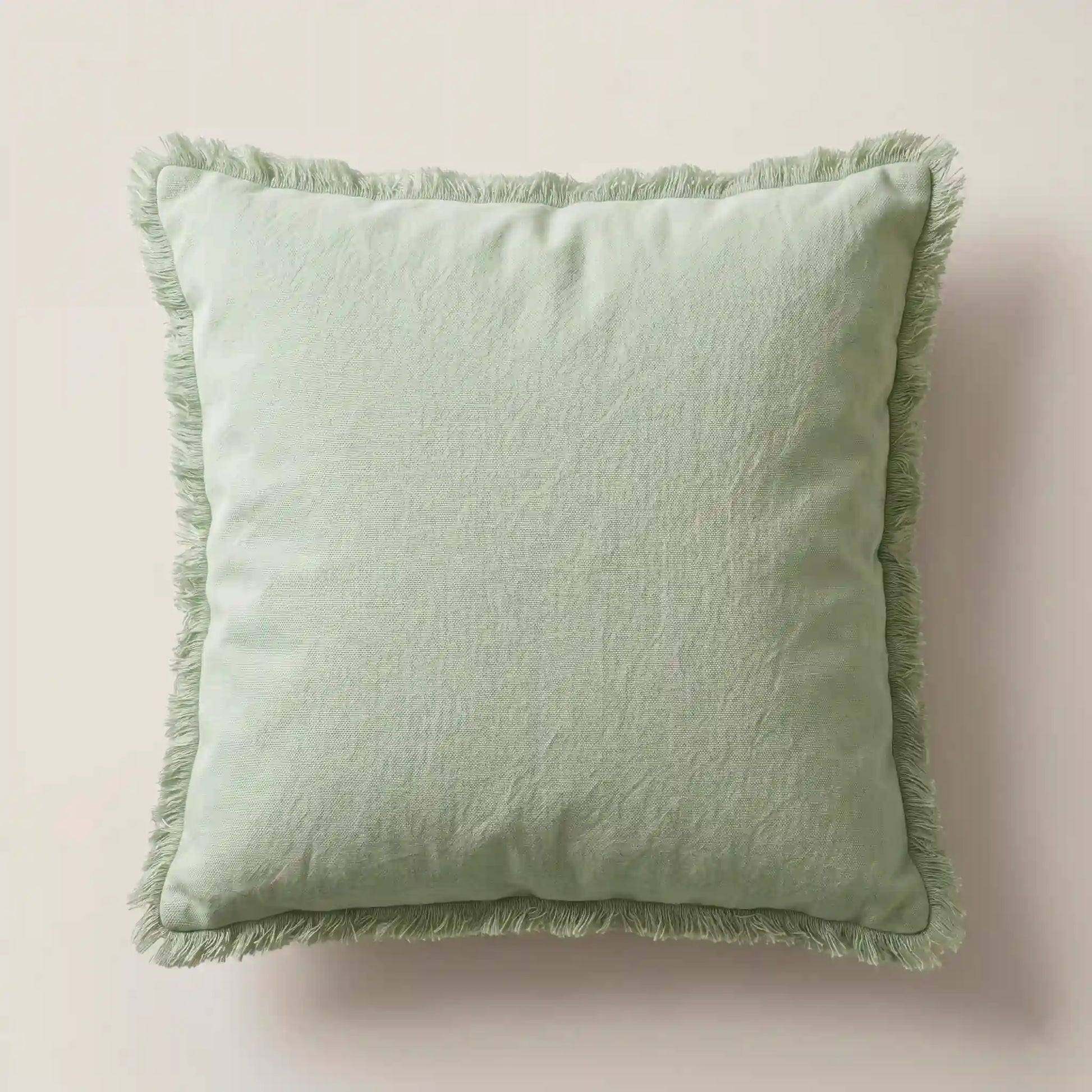 Funda de cojín verde suave 45x45cm de 100% algodón con detalles de flecos de Oma Home. Diseño natural para sofá.