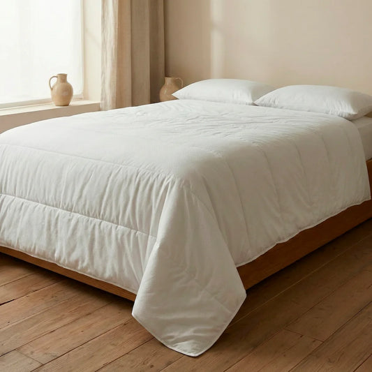 Cama de matrimonio vestida con el relleno nórdico ecológico de verano 100gr de Oma Home, mostrando su ligereza y caída natural en color blanco.